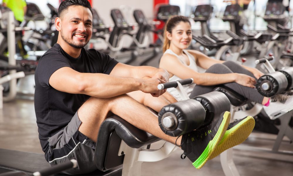 Portrait of a young Hispanic man and his girlfriend doing some crunches and exercising together in a gym